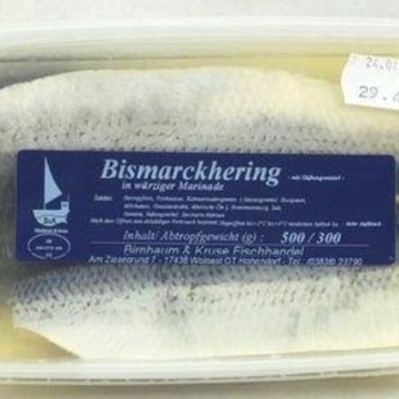 Bismarckhering in Verpackung: Eine rechteckige Kunststoffverpackung mit Bismarckhering in würziger Marinade. Auf dem Etikett stehen Zutaten und Herstellerangaben.