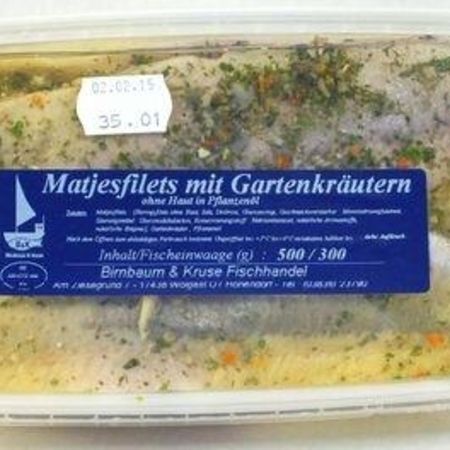 Matjesfilets mit Gartenkräutern: Fischfilets in Kräuterölmarinade mit sichtbaren Gewürzstücken und Kräutern in durchsichtiger Verpackung.