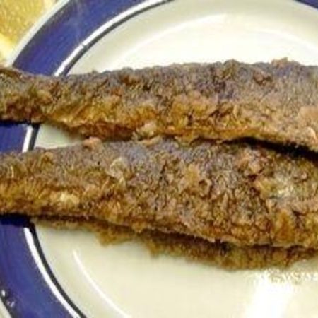 Zwei gebratene Heringe auf einem Teller mit blauem Rand serviert